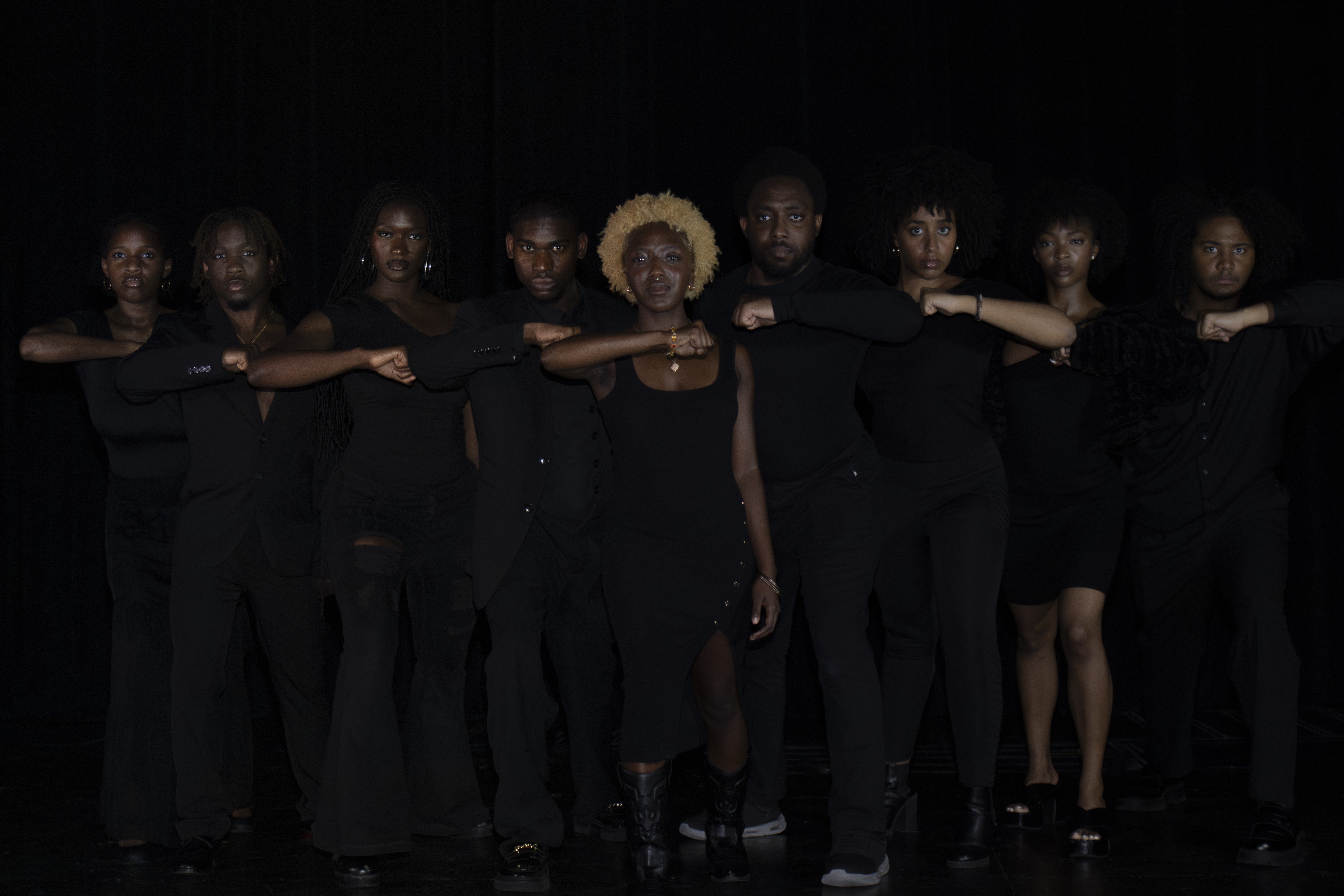 Amauriah standing with an ensemble cast on a dark stage